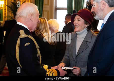 Le roi Charles III présente un emblème Elizabeth à Miranda Hong, pour Rebecca Dykes du Foreign Commonwealth and Development Office, lors de la cérémonie inaugurale de présentation au château de Windsor, Berkshire. Le roi présente le premier des emblèmes Elizabeth au proche parent des anciens pompiers, policiers et autres fonctionnaires décédés dans l'exercice de leurs fonctions. Date de la photo : mardi 10 décembre 2024. Banque D'Images