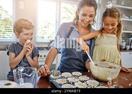 Mère, enfants et heureux dans la cuisine pour la cuisson, l'apprentissage et le garçon méchant à la maison. Famille, femme et enfants au comptoir Messy pour recette, fabrication Banque D'Images