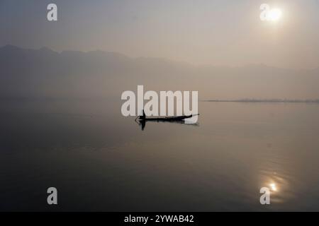 Un batelier cachemirien ramène son bateau à travers le célèbre lac Dal lors d'un matin d'hiver froid et brumeux à Srinagar. Des conditions de froid intense ont régné dans la vallée du Cachemire alors que la température minimale a chuté de plusieurs degrés en dessous du point de congélation. La capitale de la région, Srinagar, enregistre la nuit la plus froide de la saison à moins 5,4 degrés Celsius (41,72 degrés Fahrenheit), ont déclaré les responsables météorologiques dans la région himalayenne. Banque D'Images