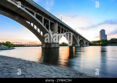 Un pont enjambe une rivière avec une ville en arrière-plan. Le pont est éclairé par des lumières, créant une atmosphère sereine et paisible Banque D'Images