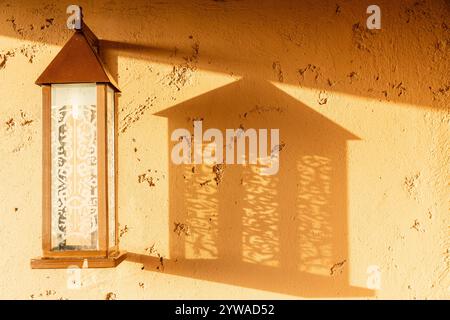 Une applique, éclairée par un soleil bas, projette son ombre sur un mur Banque D'Images