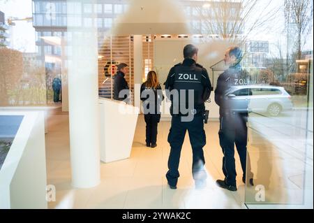 Hambourg, Allemagne. 10 décembre 2024. Les douaniers se tiennent dans la zone d'entrée du siège de l'entreprise. Soupçonnées de faux travailleurs indépendants, les autorités douanières ont procédé à des perquisitions dans plusieurs endroits en Allemagne contre des suspects d'un agent immobilier. Crédit : Jonas Walzberg/dpa/Alamy Live News Banque D'Images