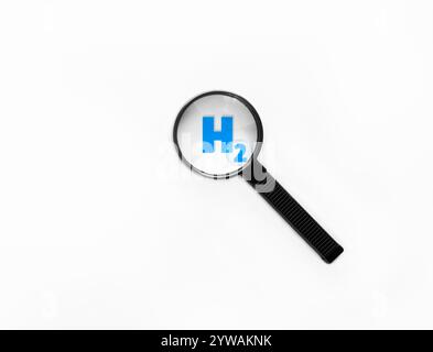 Loupe sur le symbole hydrogène en bleu. Le H2 est utilisé comme énergie renouvelable pour alimenter les futurs véhicules via une pile à combustible ou un moteur à combustion. Banque D'Images