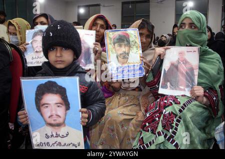 Les membres des familles des Baloutches disparus tiennent des photos de leurs proches lors du séminaire pour le rétablissement de leurs proches, dans le cadre de la Journée internationale des droits de l'homme organisée par le Comité de solidarité Baloutch, qui s'est tenu au club de presse de Quetta le mardi 10 décembre 2024. Banque D'Images
