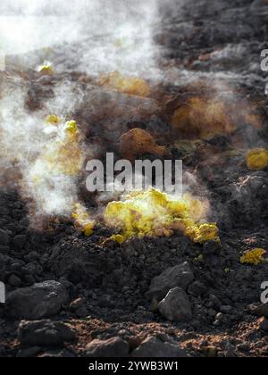 Vapeur s'élevant des minéraux de soufre sur le sol volcanique noir dans le cratère de l'île Nisyros, Grèce Banque D'Images