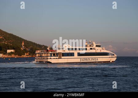 Ferry Jadrolinija quittant le port de bol au coucher du soleil, île de Brac, Dalmatie, Croatie, Europe. Banque D'Images