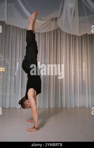Un homme se tient tête en bas sur ses mains dans la salle de gym. Banque D'Images