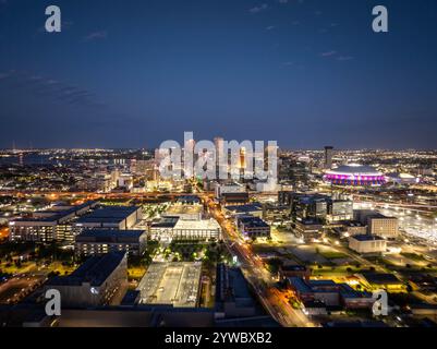 Gratte-ciel lumineux de la Nouvelle-Orléans au crépuscule avec des bâtiments illuminés, des rues animées et le Caesars Superdome, créant une vue nocturne captivante sur la ville Banque D'Images