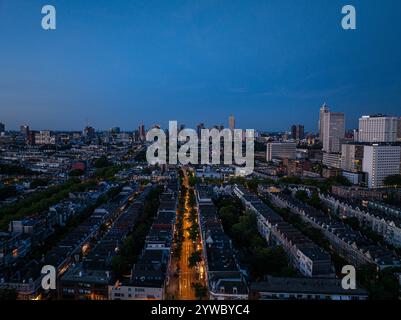 Le paysage urbain de Rotterdam au crépuscule capturé d'en haut, avec des lampadaires illuminés formant des motifs colorés au milieu des bâtiments et des arbres Banque D'Images