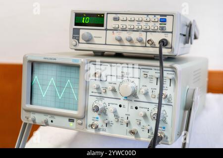 Ondes sinusoïdales vertes sur l'écran d'un oscilloscope à plusieurs boutons Banque D'Images