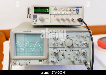 Ondes sinusoïdales vertes sur l'écran d'un oscilloscope à plusieurs boutons Banque D'Images