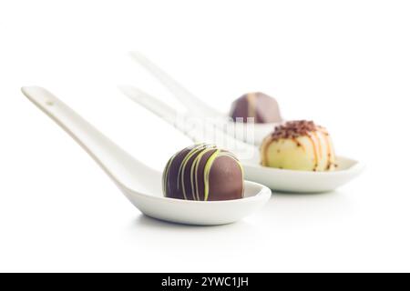 Mélange de pralines au chocolat sur cuillère isolé sur fond blanc. Banque D'Images