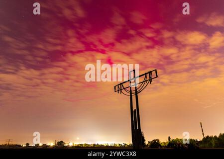 Wroclaw, Pologne - 10 mai 2024 : belle aurore rose et rouge sur le ciel vue à travers les nuages de la colline de Porto avec une grande croix sur le dessus, monument à la soldie Banque D'Images