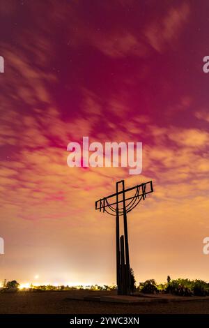 Wroclaw, Pologne - 10 mai 2024 : belle aurore rose et rouge sur le ciel vue à travers les nuages de la colline de Porto avec une grande croix sur le dessus, monument à la soldie Banque D'Images