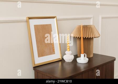 Cadre photo en bois vide avec deux chandeliers et une lampe sur un coffre dans un salon élégant Banque D'Images