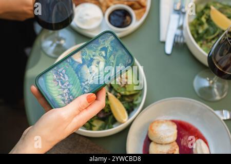 Vue aérienne d'une femme prenant une photo de son déjeuner de salade d'avocat sur son téléphone portable Banque D'Images