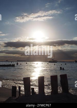 Vue verticale du coucher de soleil à Playa Norte, Isla Mujeres, Quintana Roo, Mexique avec des gens nageant dans l'océan. Concept : vacances tropicales Banque D'Images