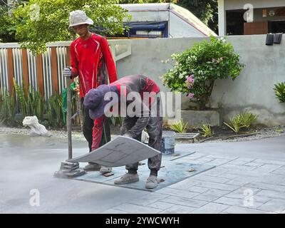 Pattaya, Thaïlande le 29 novembre 2024, deux artisans appliquent méticuleusement le béton estampé décoratif, leur technique met en évidence l'art et l'habileté impliqués dans la création de surfaces uniques. Banque D'Images