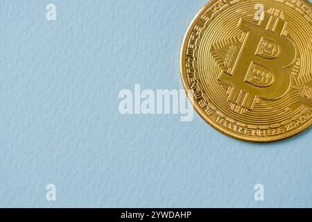Gros plan d'une pièce de crypto-monnaie Bitcoin BTC brillante dorée sur un fond bleu Banque D'Images