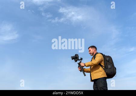 Vidéaste capturant des images en extérieur avec caméra professionnelle et stabilisateur de cardan par une journée ensoleillée Banque D'Images