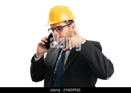 Ingénieur sérieux ou homme d'entrepreneur portant une combinaison de bureau et un casque jaune pour la sécurité faire un geste d'appel avec les doigts tout en parlant au téléphone isolez Banque D'Images