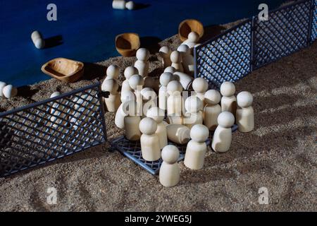 Figurines en bois et bateaux derrière des clôtures sur un sol sablonneux Banque D'Images