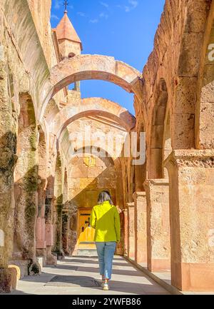 Visite de la femme marcher par les colonnes voûtées et le vieux mur de briques de l'église d'Odzun. Basilique arménienne construite entre le Ve et le VIIe siècle dans le vill d'Odzun Banque D'Images