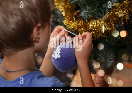 Garçon décore le sapin de Noël avec des boules créatives. Gros plan. Banque D'Images