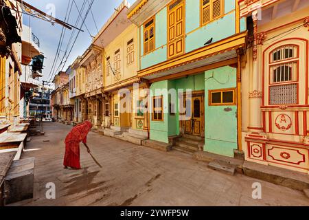 Demeures colorées traditionnelles connues sous le nom de Haveli dans la ville de Sidhpur avec une femme locale en rouge balayant à Sidhpur, Gujarat, Inde Banque D'Images