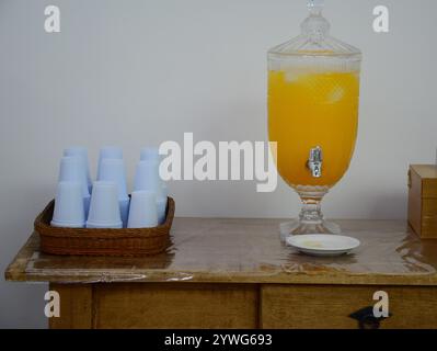 Pot en verre avec du jus jaune sur une table en bois et des verres Banque D'Images