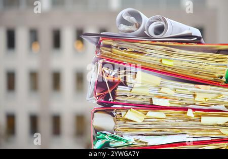 Bureaucratie, bureaucratie, obstruction des affaires, concept de politique économique chaotique. Pile de dossiers désordonnés, immeuble de bureaux floue Banque D'Images