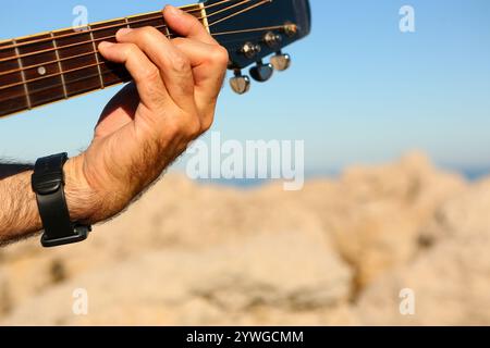Gros plan d'un homme jouant de l'accord F sur une guitare acoustique Banque D'Images