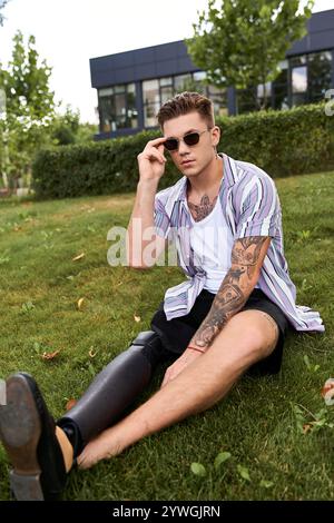 Beau jeune homme avec une jambe prothétique profite d'une journée ensoleillée dans le parc tout en regardant élégant. Banque D'Images