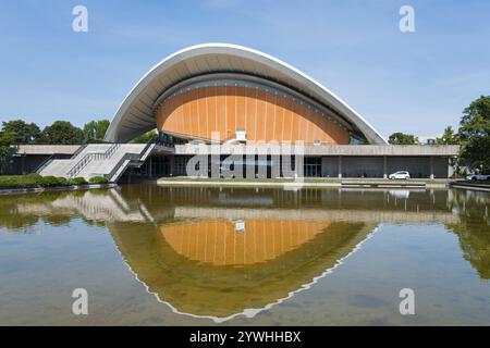 Bâtiment moderne avec toit incurvé, reflété dans l'eau contre un ciel clair, Maison des cultures du monde avec sculpture papillon, ancienne salle de congrès, Banque D'Images