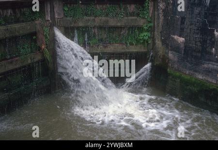 L'eau du canal s'infiltre à travers les portes d'écluse : une journée grise froide en mai à Stockton Locks L'eau du canal s'infiltre à travers un trou dans les portes d'écluse. Le vol de Stockton de 10 écluses est sur le canal Grand Union près du village historique de Stockton dans le Warwickshire. Depuis les écluses, il y a une vue imprenable sur la campagne environnante. Stockton Top Marina et le Boat Inn sont en haut du vol et le pub Blue Lias est en bas. Le Grand Union canal relie Londres et Birmingham et a été achevé au début du XIXe siècle. Les écluses de Stockton se trouvent entre Napton Junction et le village de long Itchington. Banque D'Images
