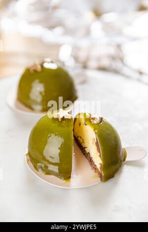 Délicieux gâteaux dôme à la pistache et au chocolat avec glaçage miroir et étoiles dorées Banque D'Images