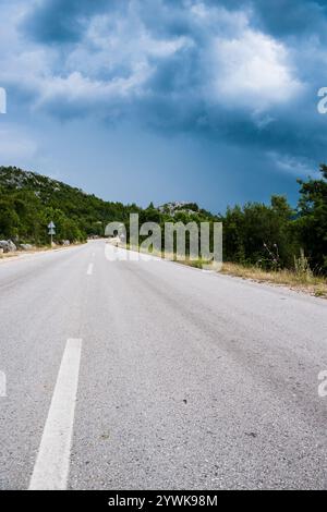 Route de campagne sinueuse par temps nuageux, offrant un voyage pittoresque et serein à travers la nature rurale et les paysages d'automne Banque D'Images