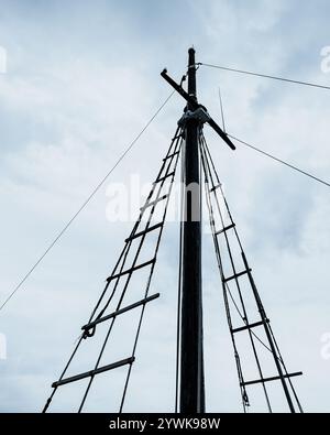 Mât de navire en bois simple avec gréement nautique contre un ciel nuageux spectaculaire, mettant en valeur le patrimoine maritime et les traditions maritimes Banque D'Images