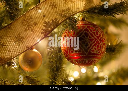 Gros plan sur des boules colorées et un ruban suspendu à un sapin de Noël Banque D'Images
