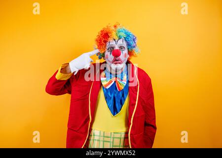 Clown souriant pointant, fond jaune vif, plaisir. Banque D'Images