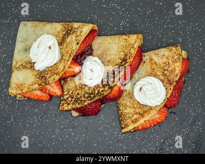 crêpes aux fraises et crème et chocolat servis sur ardoise Banque D'Images