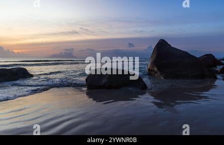 Beau Vallon Beach paysage avec sable humide et silhouettes de rochers côtiers sur le coucher du soleil. Île de Mahé, Seychelles Banque D'Images