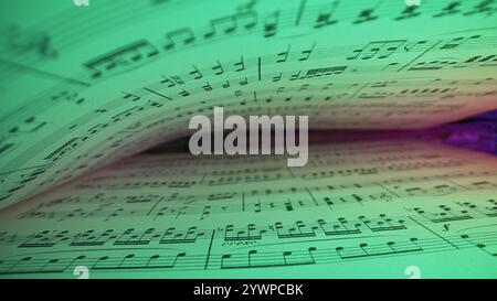 Macro arrière-plan de livre médiéval sauvegardé avec des écrits de notes musicales anciennes, lumière néon éclatante. Texture de la vieille symphonie classique manuscrite Banque D'Images