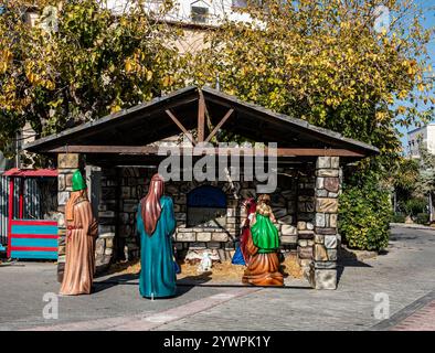 Des personnages festifs grandeur nature entourent une scène rustique de nativité, célébrant la naissance de Jésus dans les rues de Kos, en Grèce. Banque D'Images