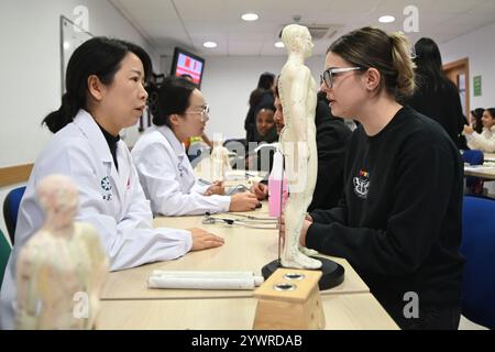 Msida, Malte. 11 décembre 2024. Les membres de la 20ème équipe médicale chinoise pour Malte offrent des consultations médicales gratuites et des services cliniques aux étudiants de l'Université de Malte à Msida, Malte, le 11 décembre 2024. Les étudiants maltais ont découvert la médecine traditionnelle chinoise (MTC) et la langue chinoise cette semaine, dans le cadre d’une expérience culturelle unique organisée par l’Institut Confucius de l’Université de Malte. Crédit : Jonathan Borg/Xinhua/Alamy Live News Banque D'Images