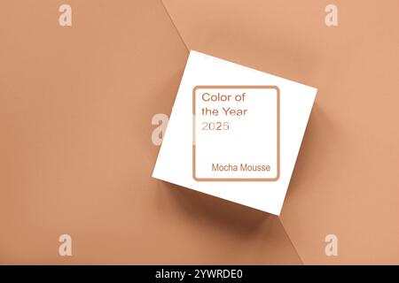 Pose à plat minimaliste d'une carte affichant la « couleur de l'année 2025 Mocha mousse » sur fond beige, avec espace copie. Banque D'Images