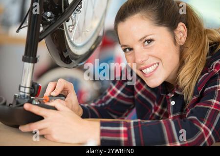 jeune femme réparant un vélo dans un atelier Banque D'Images