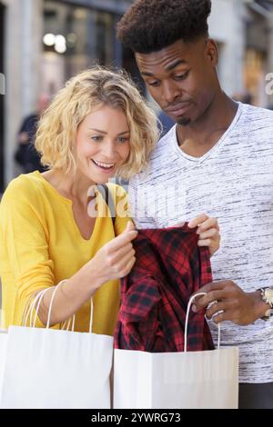 jeune couple mixte regardant des sacs à provisions eachothers Banque D'Images