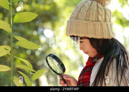 Fille en bonnet tricoté avec loupe Banque D'Images