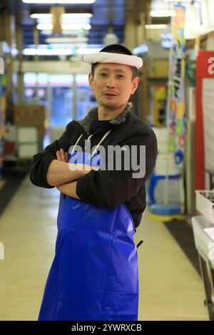 Commis masculin dans un magasin de poisson frais debout dans l'allée du marché Banque D'Images